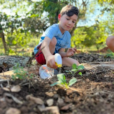 Criança regando mudinha na horta da Fazenda Luz300